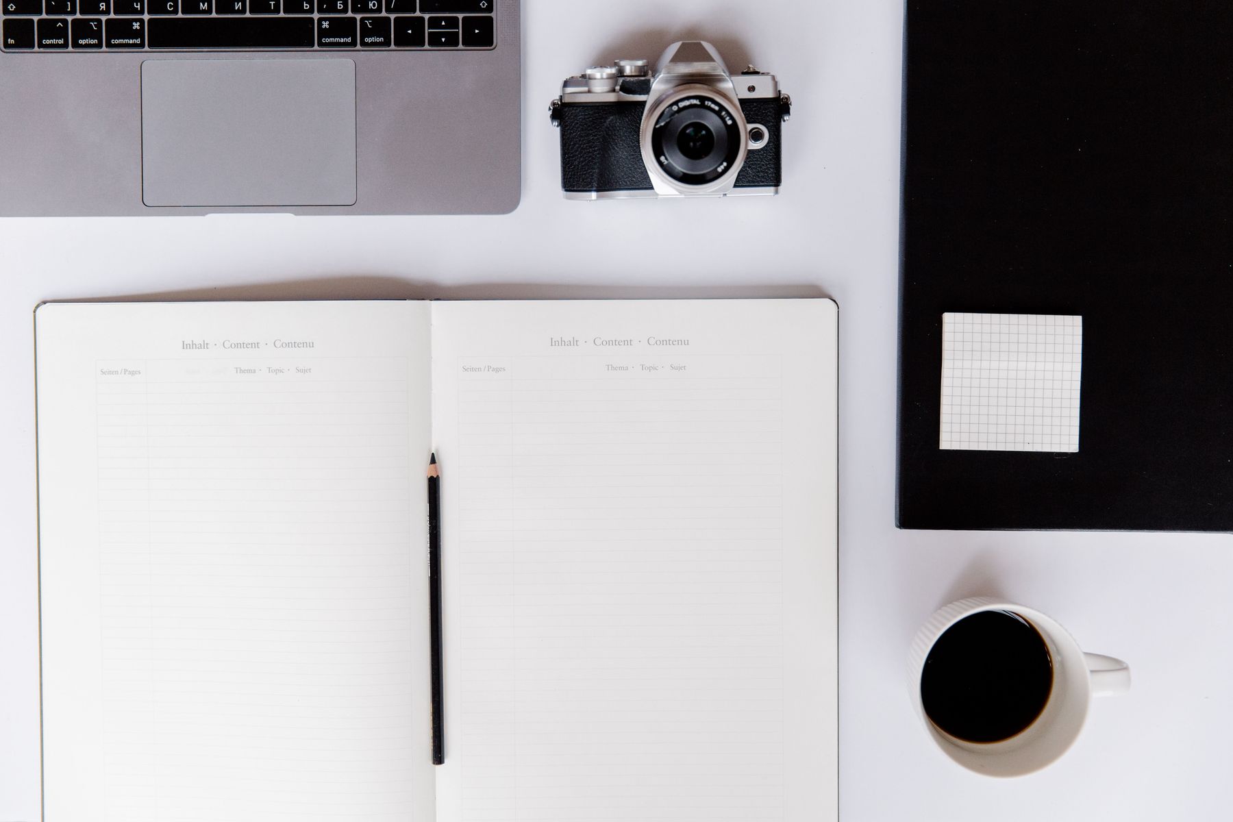 A camera, notebook and coffee on a creative desk. Stock concept photograph.